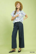 A woman wears a mixed media blouse shirt with a blue and white geometric print and button front collared design