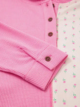 Pink waffle-knit long-sleeved henley shirt with brown buttons featuring slightly stretchy fabric and care instructions