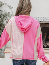 Back view of a vibrant pink and beige floral patchwork waffle knit hoodie with slightly stretchy fabric and care instructions label visible