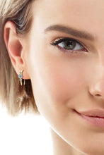 Womans ear with gold hoop sterling silver earrings and three clear moissanite stones