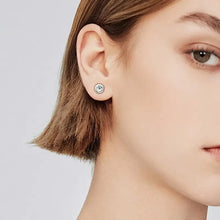 Woman in single bezel-set cubic zirconia sterling silver stud earring