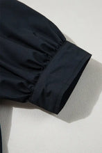 Black nylon rain jacket sleeve with elastic hem on navy blue puff sleeve dress