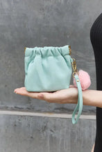 Nicole Lee USA faux leather pouch features mint green drawstring with gold-tone hardware and pink pom-pom charm