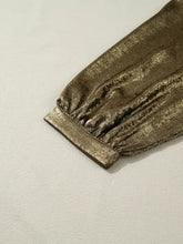 The metallic gold textured fabric cuff of a notched 3/4 sleeve blouse showcases elegant sleeve blouse detail