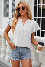Woman in notched cap sleeve T-shirt, denim shorts, holding coffee