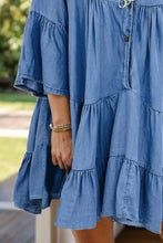 A soft blue denim dress with notched flare sleeves, tiered ruffles, and button-front design in flare sleeve denim