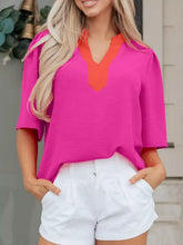 A vibrant fuchsia notched half sleeve blouse with a contrasting orange v-neckline and short puffed sleeves
