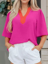 A vibrant fuchsia notched half sleeve blouse with contrasting orange v-neckline and puffy short sleeves