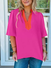 A vibrant pink notched half sleeve blouse with orange v-neckline and puffed short sleeves in lightweight fabric