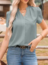A soft sage green lightweight blouse with a notched v-neckline and puffed short petal sleeves