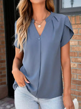 A soft blue short-sleeved notched petal sleeve blouse with a v-neckline and ruffled shoulder details