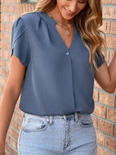 A soft blue notched petal sleeve blouse with short sleeves v-neck and button-front design in lightweight fabric