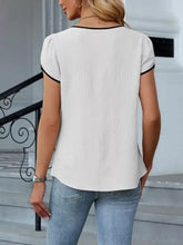 White short-sleeved notched petal blouse with black trim at neckline and cuffs made of lightweight fabric