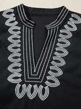 Black notched puff sleeve blouse with intricate white embroidery along the neckline and front opening