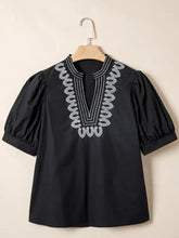 Black short-sleeved notched puff sleeve blouse with white embroidered detailing along the v-neckline