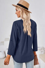Woman in navy blue v-neck long-sleeved Notched Roll-Tab Sleeve T-Shirt and tan fedora