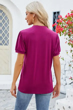 Woman in magenta notched short sleeve T-shirt and blue jeans