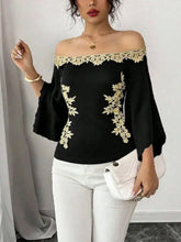 Black off-the-shoulder top with gold floral embroidery lace trim featuring embroidered bell sleeve design