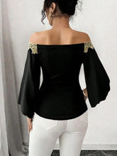 Black off-shoulder top with gold embroidered bell sleeve lace detailing at the shoulders and bell sleeves