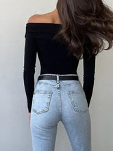 Light-wash denim jeans with a high-rise fit and classic back pockets paired with an off-shoulder ruched long sleeve bodysuit
