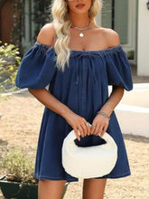 White fluffy circular handbag with black handle and interior paired with off-shoulder tie-front denim dress