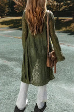 Olive green long sleeve cardigan with embroidered bell sleeves and white pants