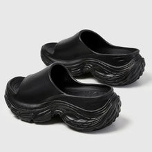 Pair of black chunky open toe platform slippers with wavy sole