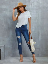 Woman in openwork short sleeve round neck top, jeans, sandals, and bag