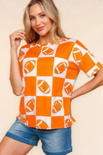 Woman in orange and white football checkered print short sleeve t-shirt