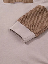 Beige oversize waffle patchwork hoodie with exposed seam, long sleeves, contrasting tan waffle-knit cuff, and ribbed hem
