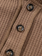 Brown ribbed knit cardigan features dark glossy buttons with oversize waffle patchwork exposed seam design