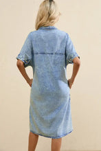 A light blue oversized button down denim shirt dress with short sleeves, collar, rolled cuffs, and relaxed fit