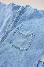 Light blue oversized denim shirt dress with silver buttons and a front pocket featuring denim material