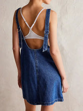 Back view of oversized v-neck blue denim tank dress with white adjustable straps and front pockets safe for machine wash