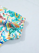 Vibrant paisley floral printed swim trunks in white teal blue yellow and brown complementing a floral printed puff sleeve blouse