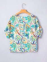 A vibrant paisley floral printed puff sleeve blouse with short sleeves in teal yellow and blue on white background