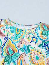 A vibrant white paisley floral printed blouse with teal yellow and brown printed puff sleeves