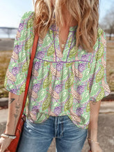 A light green paisley print half puff sleeve blouse with purple beige pattern and short flutter sleeves with v-neckline