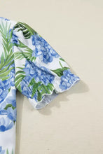 White dress with vibrant blue hydrangea and green leaf pattern featuring ruffled neck short sleeve and striped patchwork design