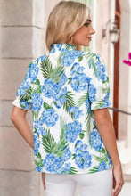 A woman wears a white palm floral print striped patchwork neck short sleeve blouse with blue hydrangea and green leaves