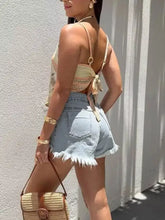 A woven straw handbag with brown leather handle and buckle accompanies the parrot adjustable strap cami with wooden bead straps