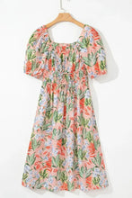 Pastel floral print summer dress with puff sleeves and tie waist on light pink background