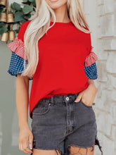 Patriotic short sleeve round neck top in red with ruffled sleeves featuring stars and stripes design at cuffs