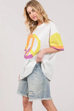 White peace applique t-shirt with fig color block and frayed denim skirt