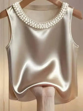 A shimmering silver pearl embellished satin sleeveless tank top with delicate pearls along the neckline