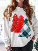 White long-sleeved drop shoulder sweatshirt with three appliquéd christmas trees in red green and plaid patterns