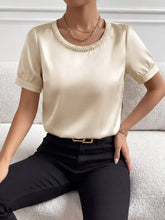 Cream-colored pearl trim satin bodysuit with a pearl-trimmed neckline and puffed short sleeves
