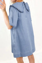A light blue denim dress with a peter pan collar frayed ruffle and short sleeves