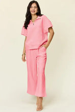 Woman in pink zip short sleeve collared top and wide leg cropped pants set
