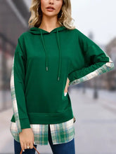 Woman’s dark green drawstring long sleeve slit hoodie with plaid shirt layer